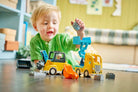 A close-up view of a child's hands using the tipping bucket loader to dump a boulder block into the DUPLO dump truck.